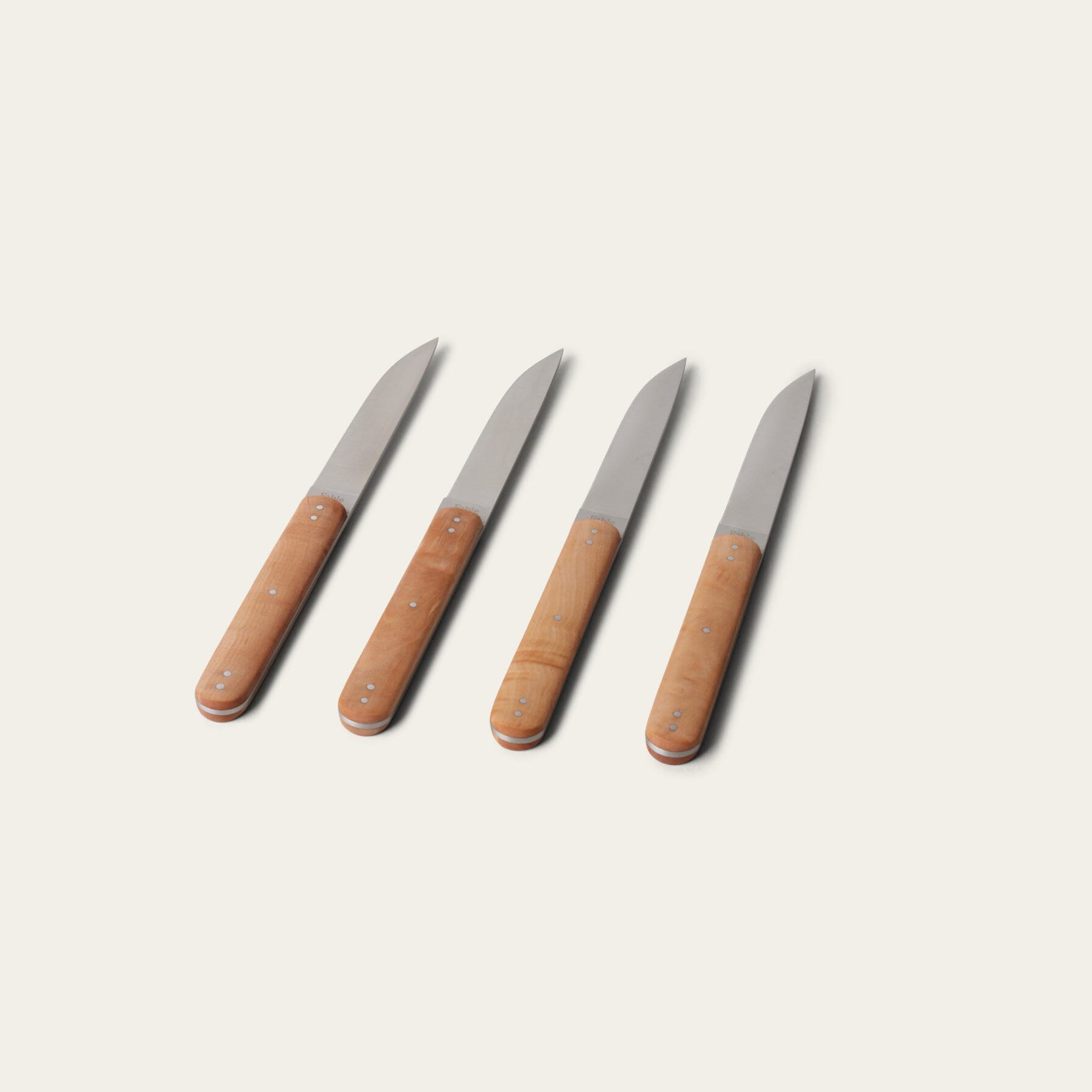 Four knives with brown handles on a light beige background